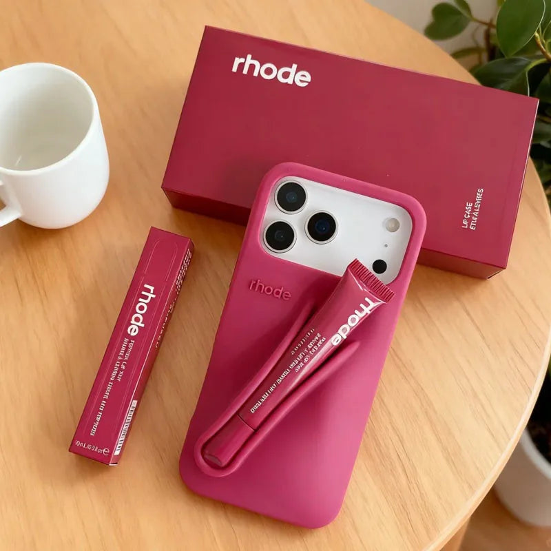 Pink Rhode phone case with matching pen and box on a wooden surface, featuring the 'rhode' brand.