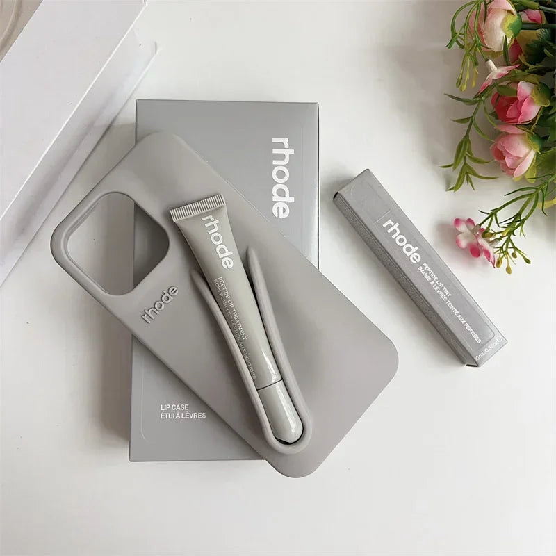 Gray 'rhode' beauty product set on a white surface with flowers in the background
