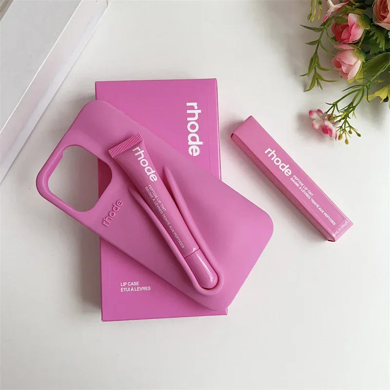 Pink lip liner set with 'rhode' branding on a white surface with flowers.