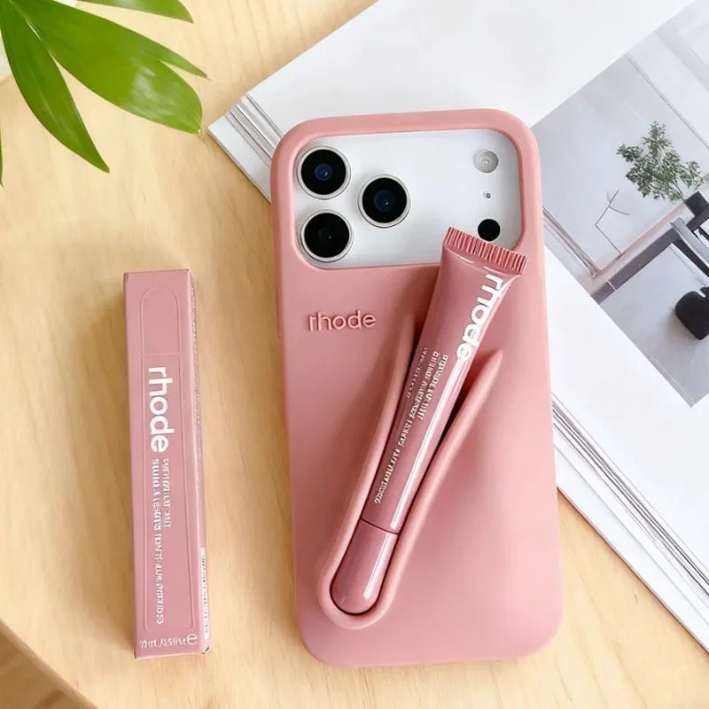 Pink phone case with pen and Rhode branding on a wooden surface