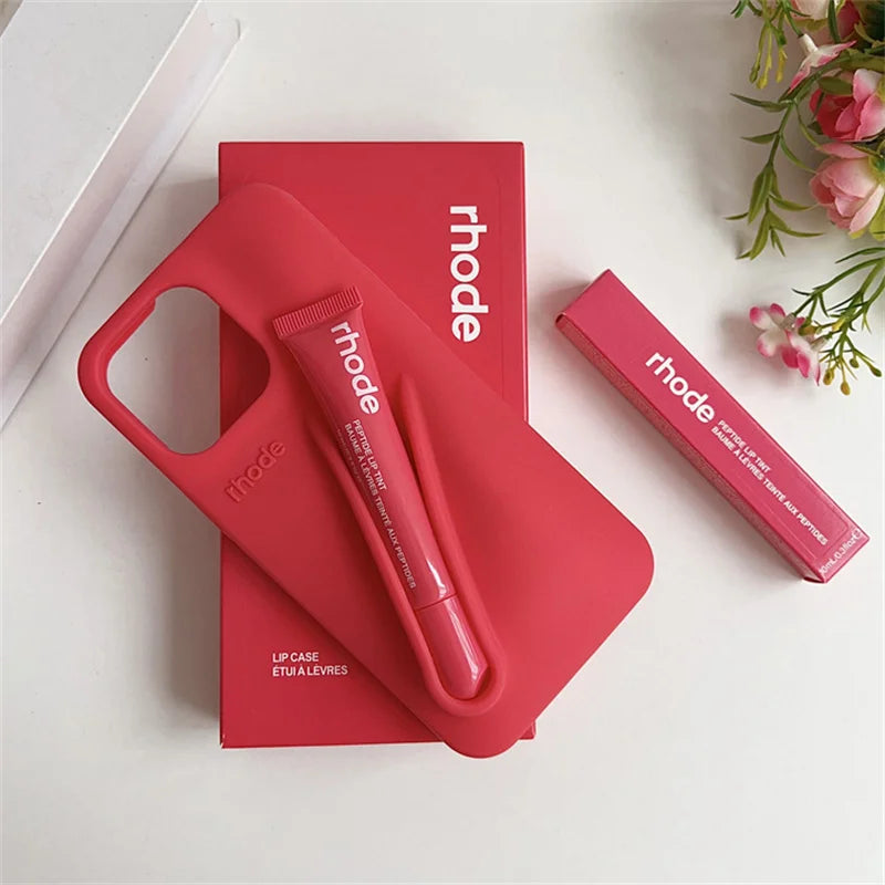 Red lip case and lip balm with 'rhode' branding on a white surface with flowers.