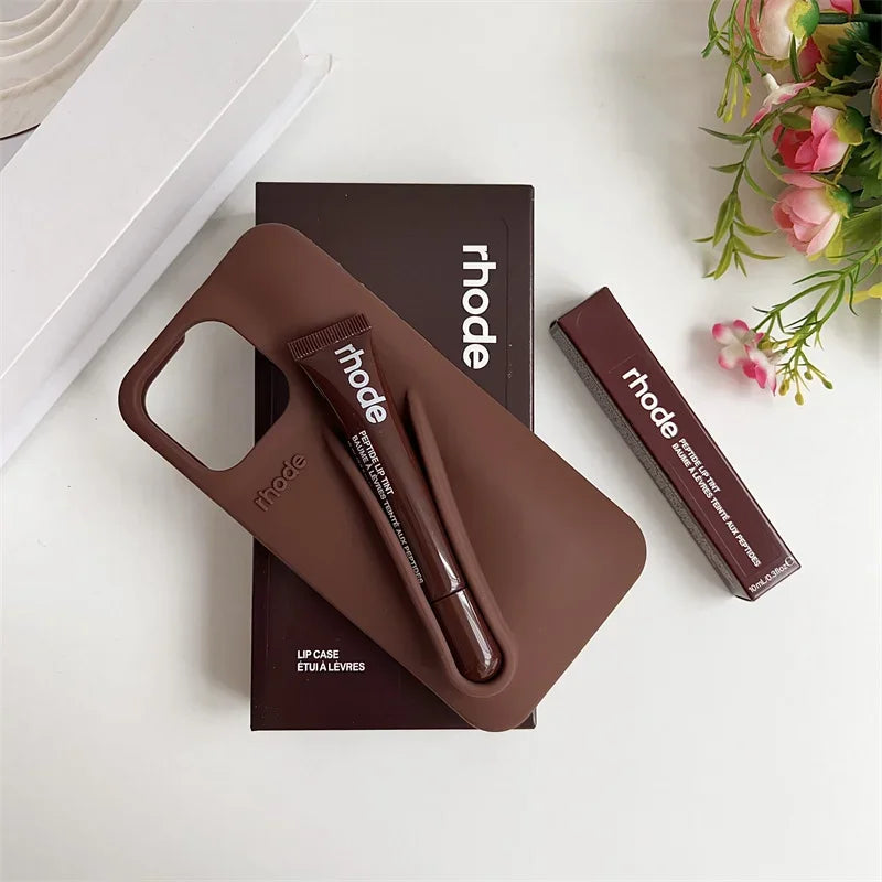 Brown lip case with lip balm and packaging on a white surface with flowers.