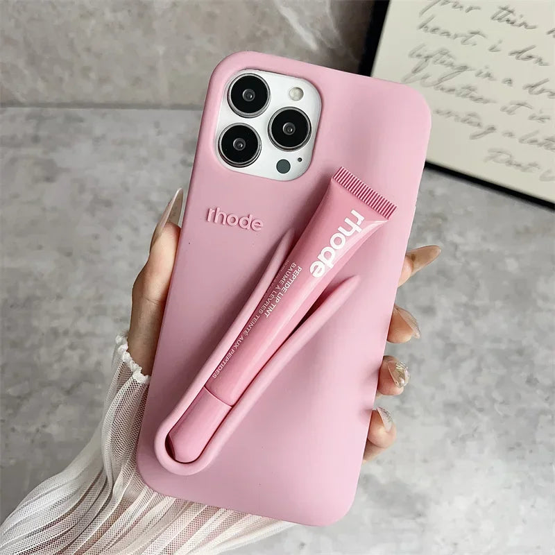 Pink Rhode phone case with a pen holder attached, held by a hand on a neutral background.