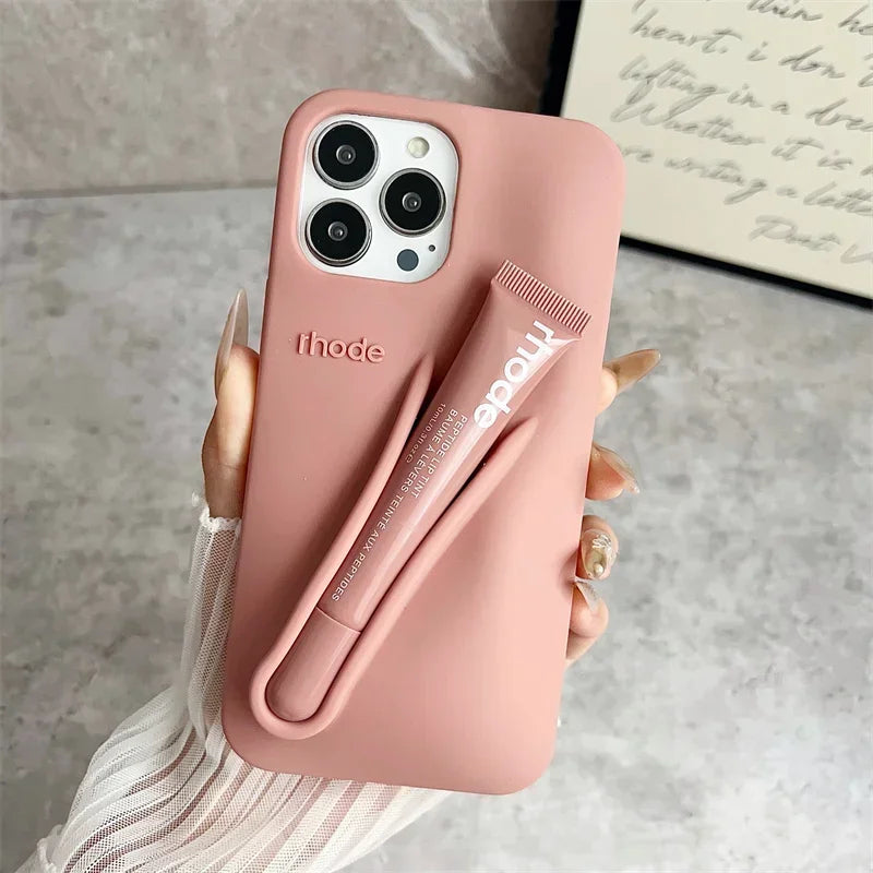 Pink phone case with a liptins holder attached, held by a hand on a neutral background.